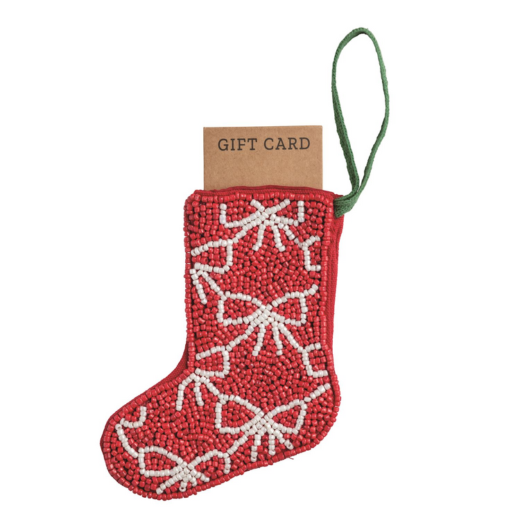 Red beaded stocking ornament with white bow patterns and a green loop, holding a brown gift card.