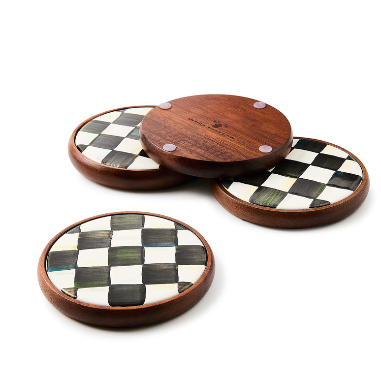 Set of 4 round coasters with acacia wood bases and hand-painted black and white checkered plates.
