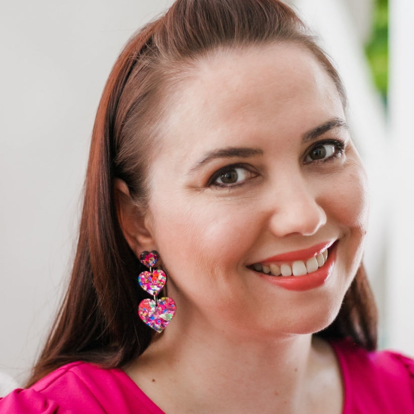 Sparkling heart-shaped sequin earrings with laser-cut acrylic bodies on surgical steel studs.
