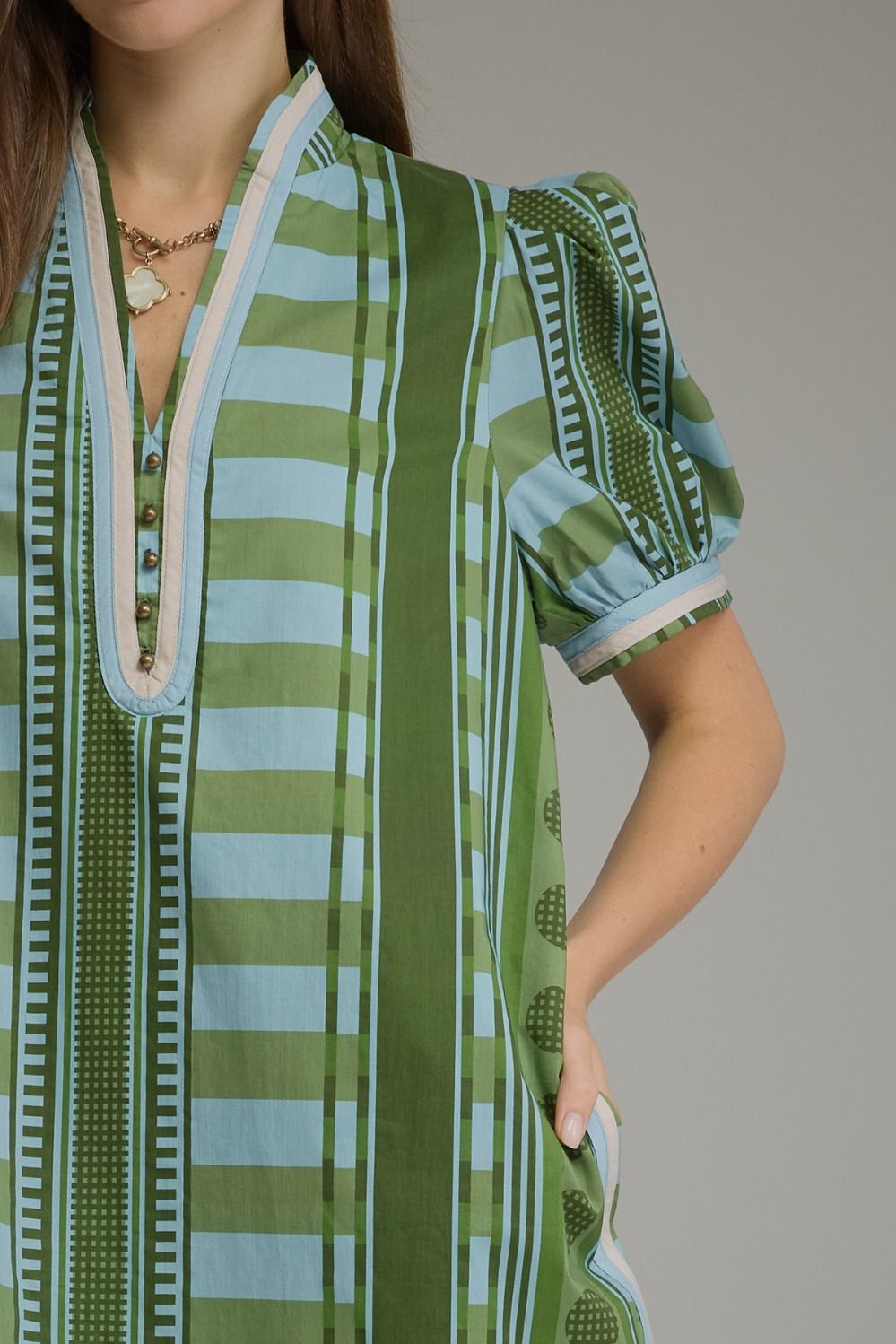 Close-up of Gabrielle mini dress in green and blue stripes with puff sleeves and button V-neck.