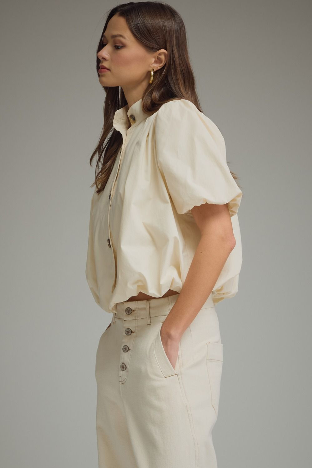Woman wearing a cream Jacky Short Puff Sleeve Top with a bubble hem and band collar.