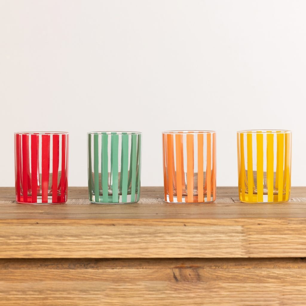 Four handblown glass juice glasses with red, green, orange, and yellow vertical stripes.