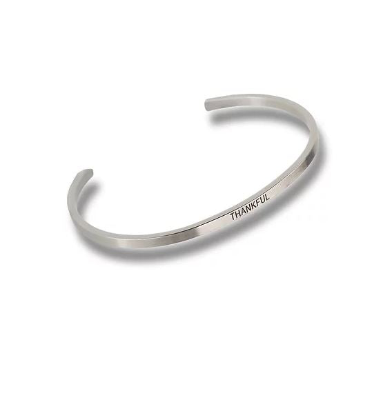 Silver-toned metal cuff bracelet with the word THANKFUL engraved on the outer surface.