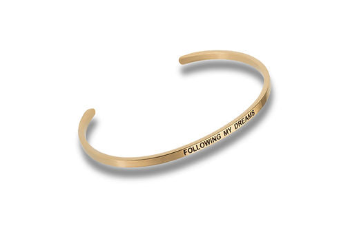 Gold-tone metal cuff bracelet engraved with the text FOLLOWING MY DREAMS.