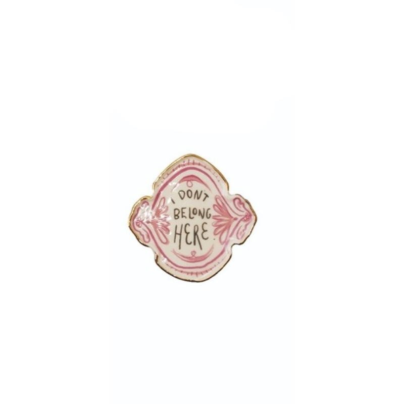 Decorative stoneware magnet with pink accents and text reading "I DON'T BELONG HERE".