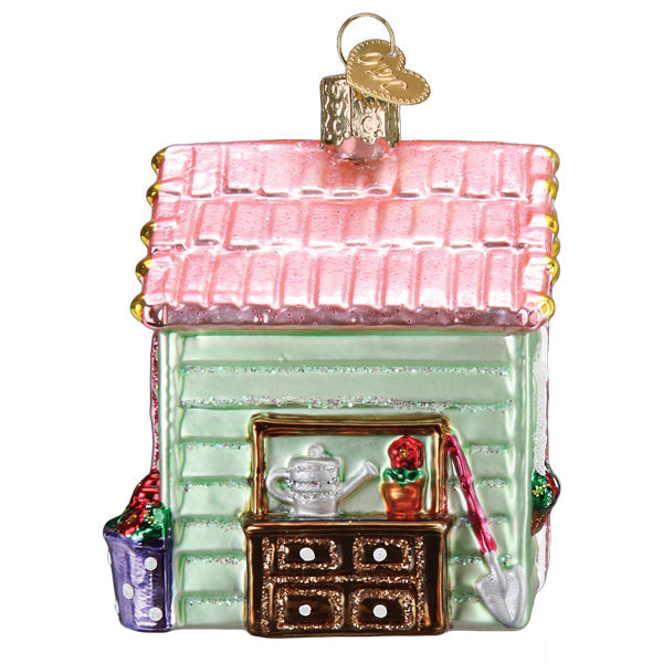 Glass She Shed Christmas ornament with a pink roof, light green walls, and gardening tools.