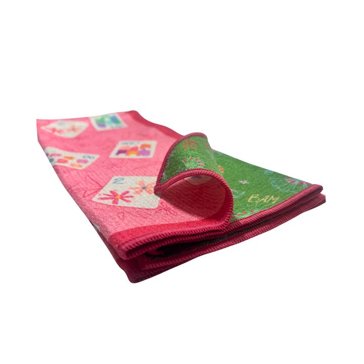 Folded pink and green double-sided tea towel with colorful mahjong tile illustrations.