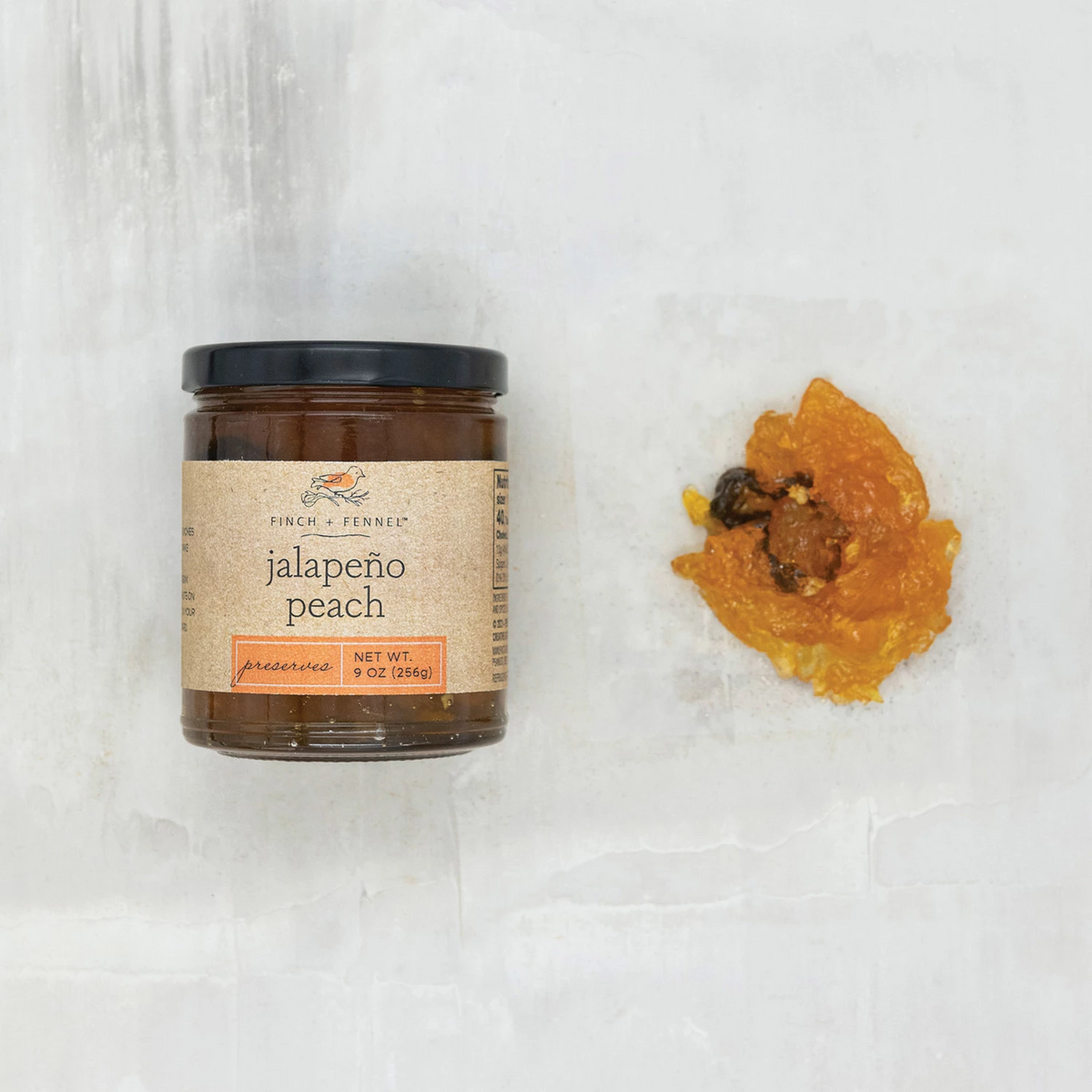 Glass jar containing jalapeno peach preserves with visible fruit pieces.