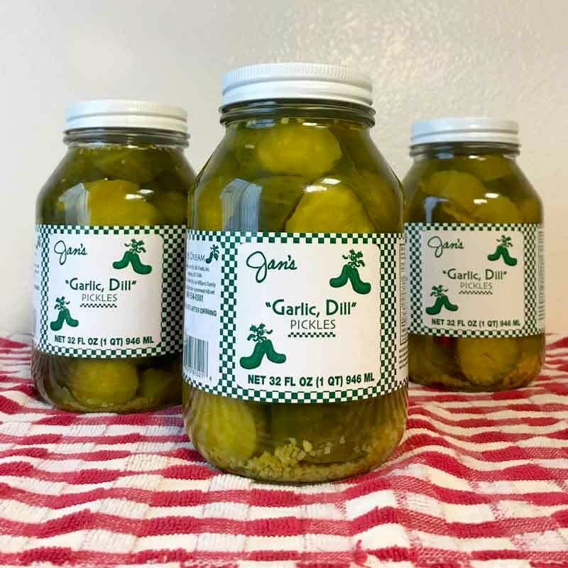Glass jar containing Jan's Pickles combination spicy sweet garlic dill pickle with visible vegetables in brine