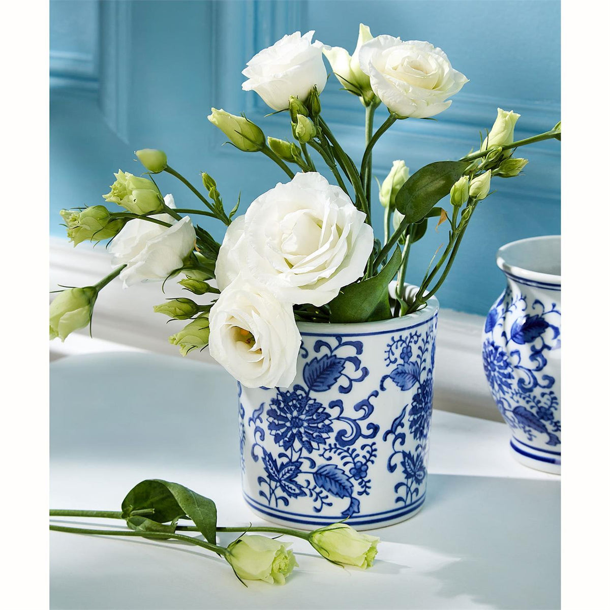 Small cylindrical ceramic vase with hand-painted blue and white chinoiserie floral patterns.
