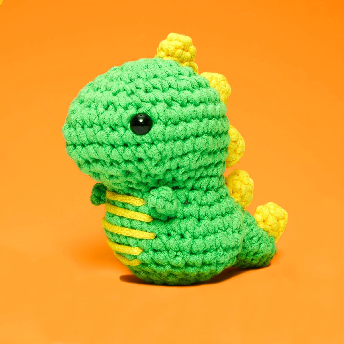 Fred the Dinosaur crochet kit featuring a PDF pattern, ergonomic hook, yarn, stuffing, and plastic eyes.