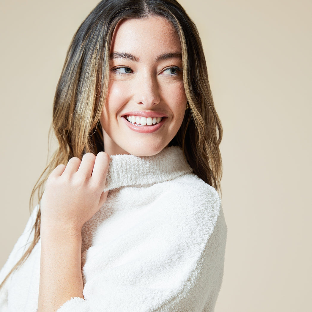 Woman wearing a cream-colored Solid Marshmallow Shrug in Almond with a soft, textured finish.