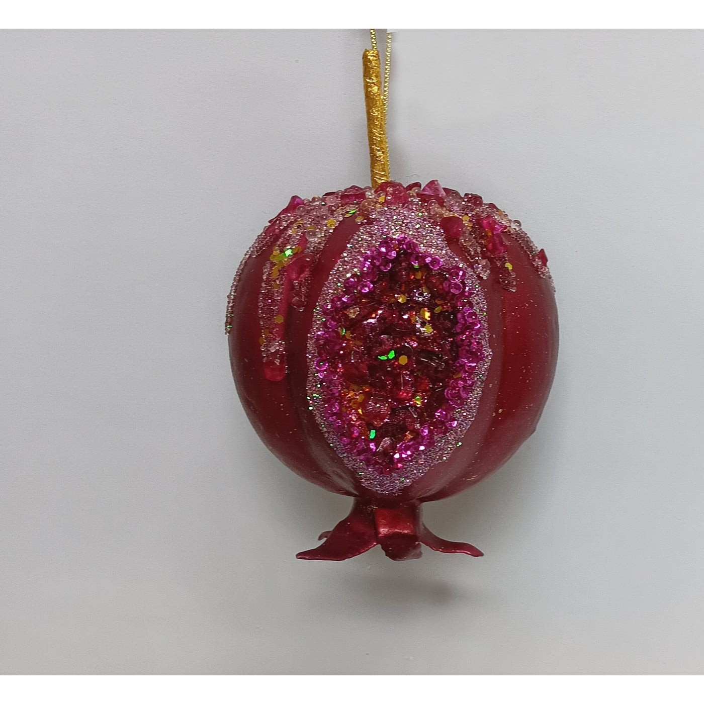 Red pomegranate ornament with a split-open front revealing shimmering faux seeds and a gold hanger.