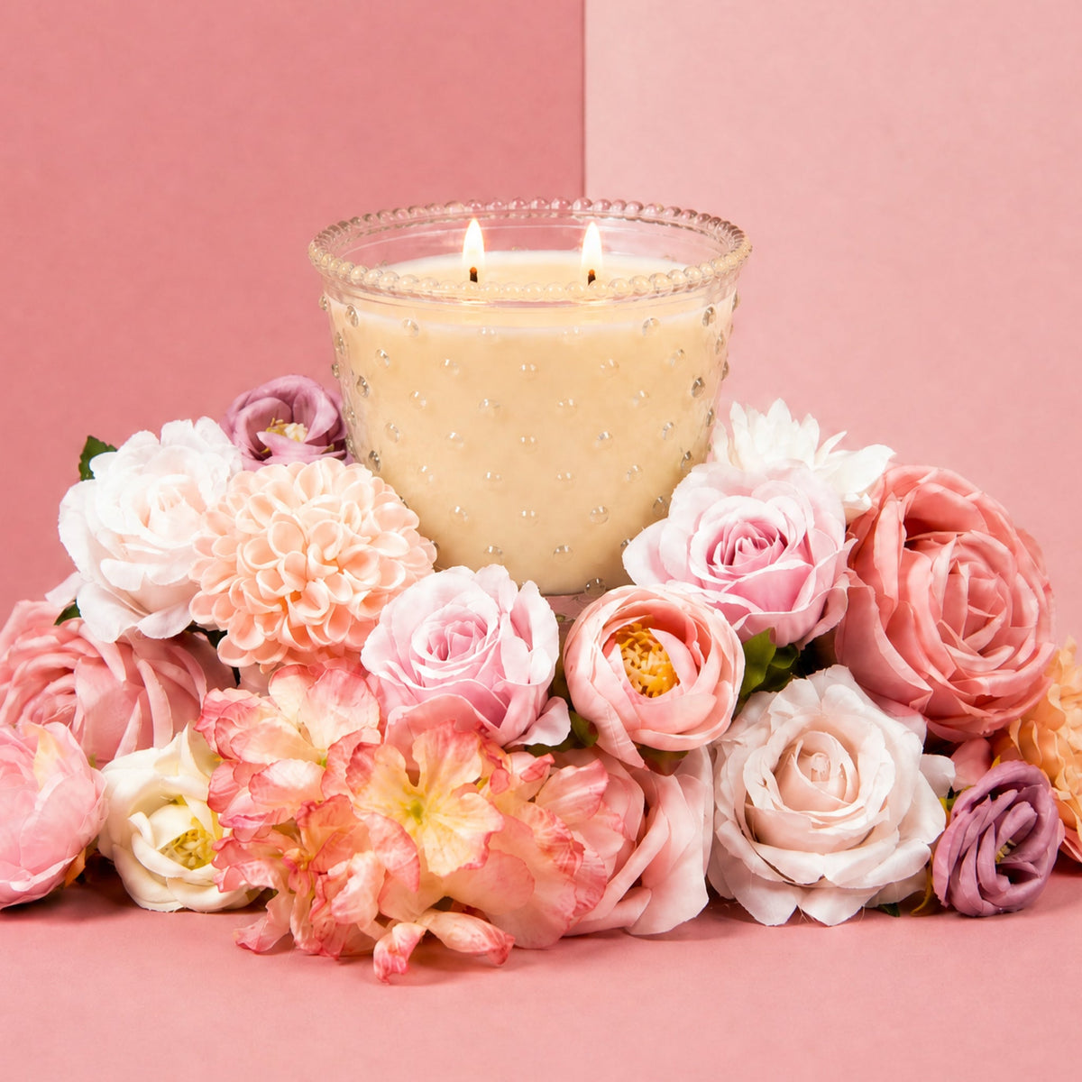 Sweet Grace Collection Candle #080 in a clear hobnail glass vessel surrounded by pink flowers.