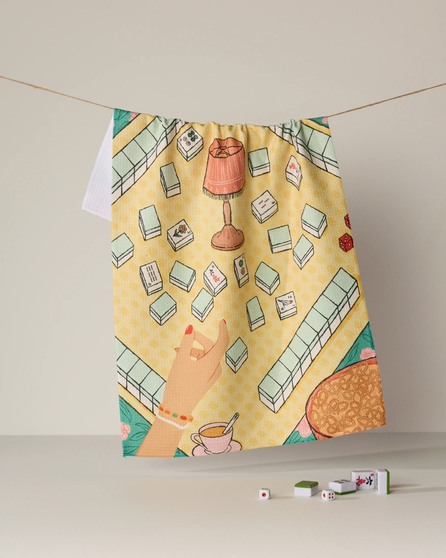 Everyday Tea Towel hanging on a line, featuring a colorful illustration of a mahjong game scene.