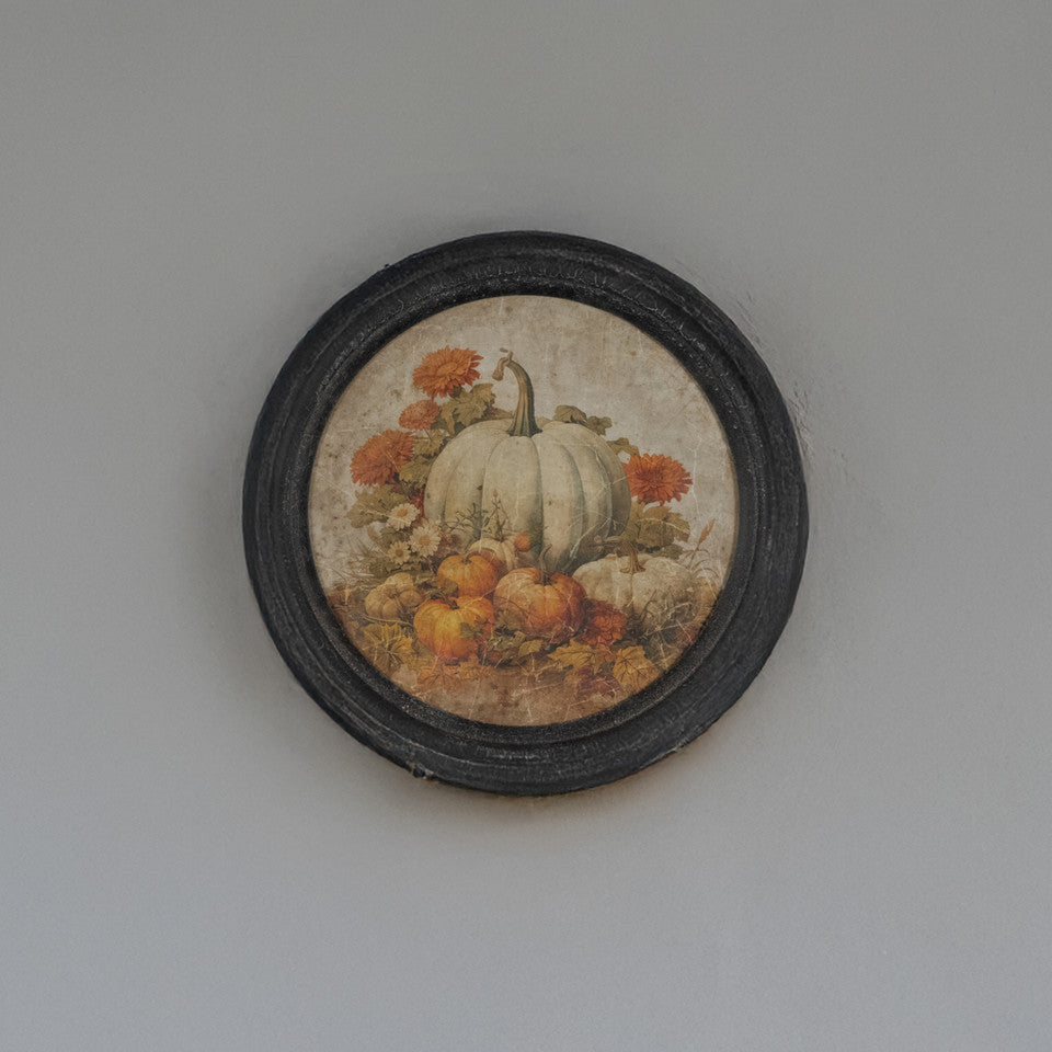 Round black wood framed print featuring a large white pumpkin and smaller orange pumpkins.