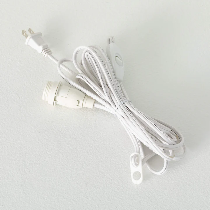 White electrical cord with a white fabric sleeve covering the wire.
