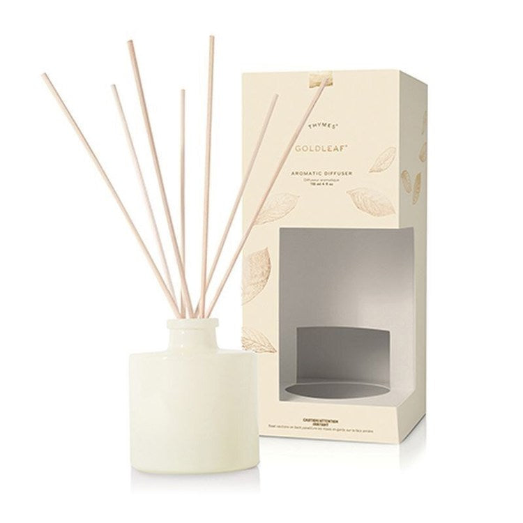 Petite gold leaf aromatic diffuser with a cylindrical glass body and metallic finish.