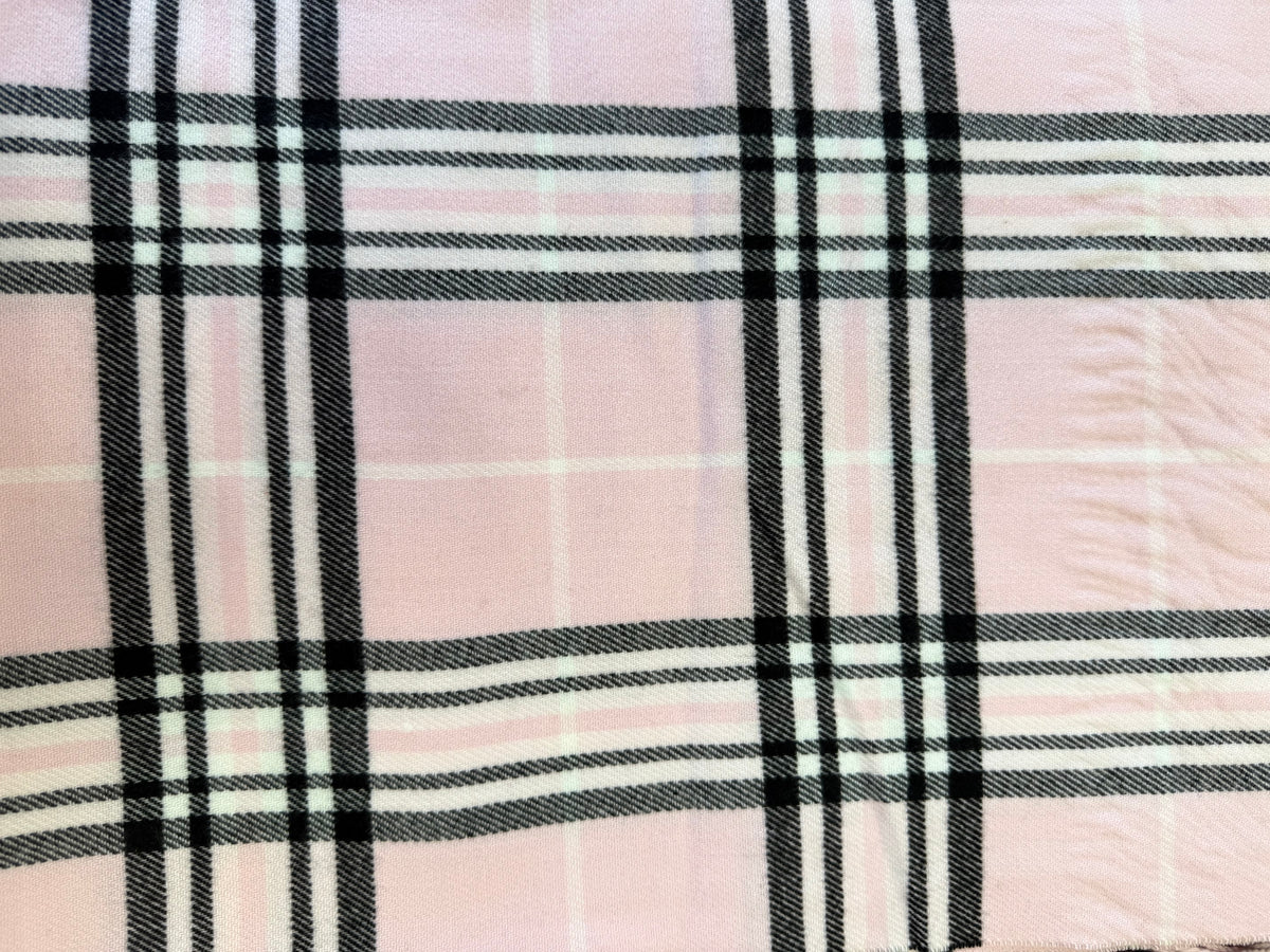 Close-up of a pink Scottish plaid cashmere scarf with black and white intersecting stripes.
