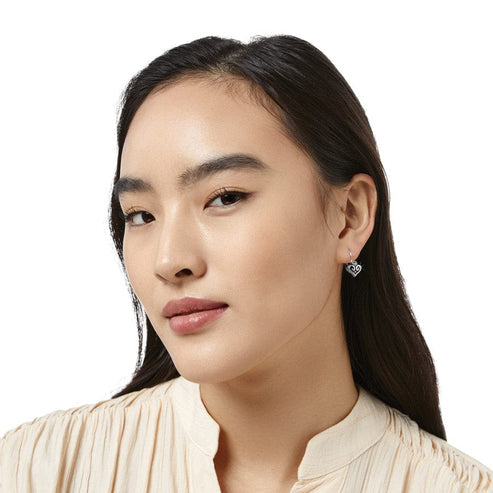 A woman wearing the Alcazar Heart Leverback Earrings in silver.