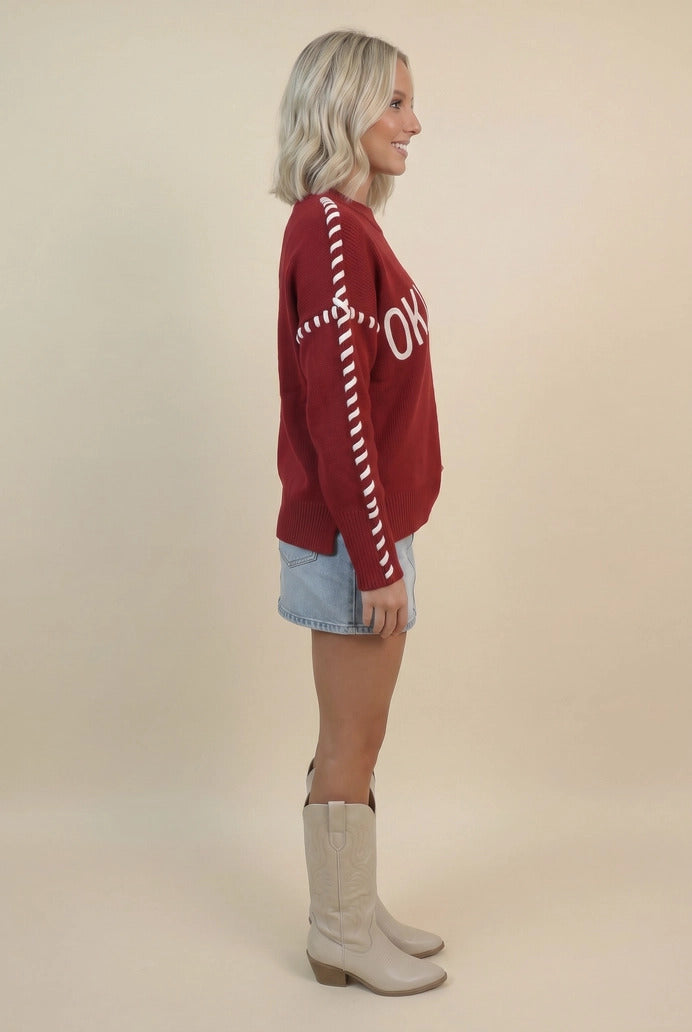Side view of a woman wearing a red Oklahoma sweater with white whip stitch details on the sleeves.