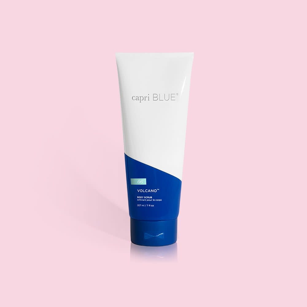 Capri Blue Volcano Body Scrub in a 7 oz white and blue squeeze tube against a pink background.