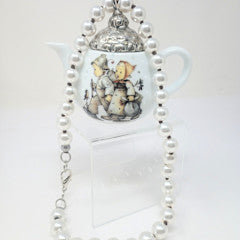 Porcelain teapot charm with M.I. Hummel artwork on an 18-inch pearl necklace