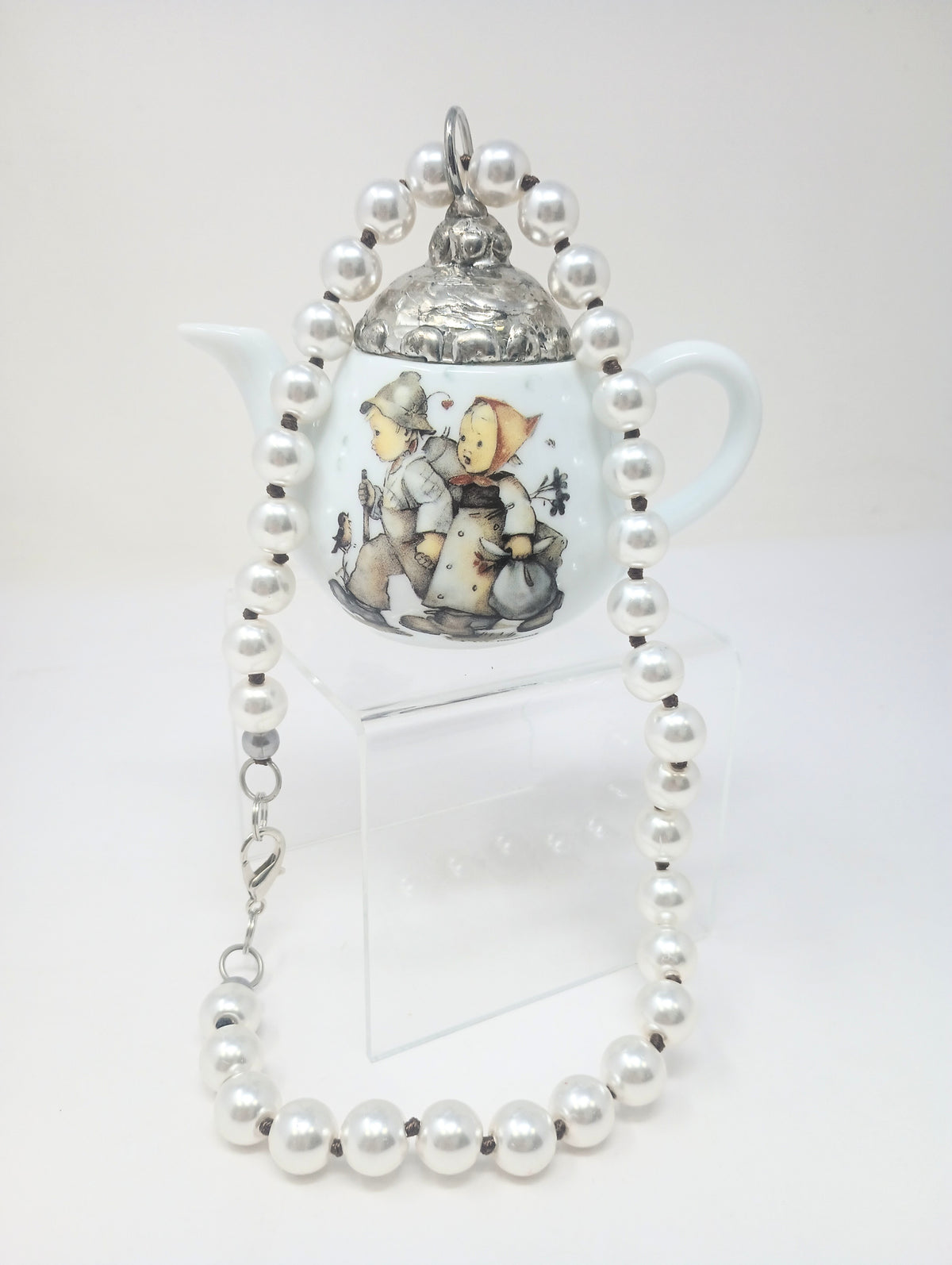 Porcelain teapot charm with M.I. Hummel artwork on an 18-inch pearl necklace