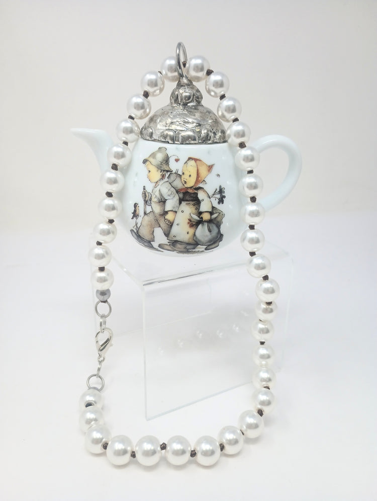 Porcelain teapot charm with M.I. Hummel artwork on an 18-inch pearl necklace