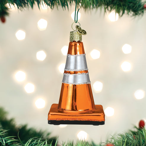 Orange and silver traffic cone glass Christmas ornament hanging from a tree branch.