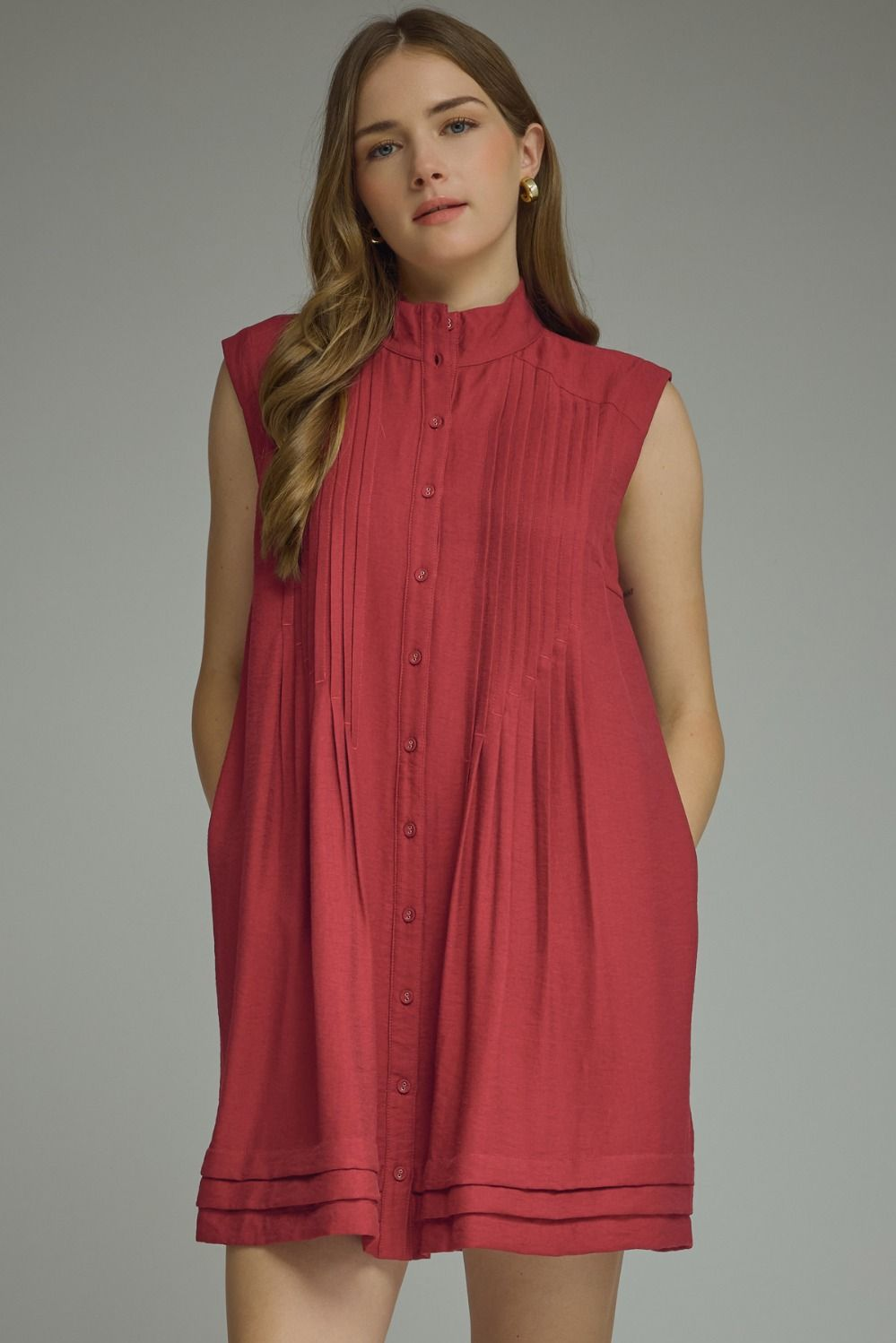 Woman wearing Thea D31604, a sleeveless red mini dress with a high neck and pleated front detail.