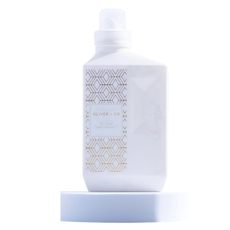 White bottle of Oliver + Co Supreme Laundry Wash in St. Lucia scent with gold geometric patterns.