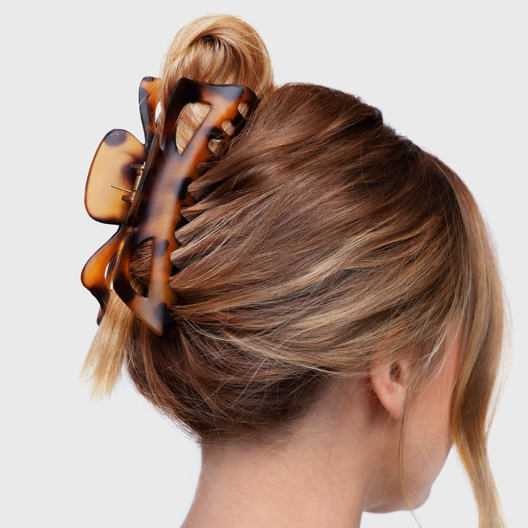 A woman wearing a large tortoiseshell-patterned jumbo classic claw clip in her blonde hair.