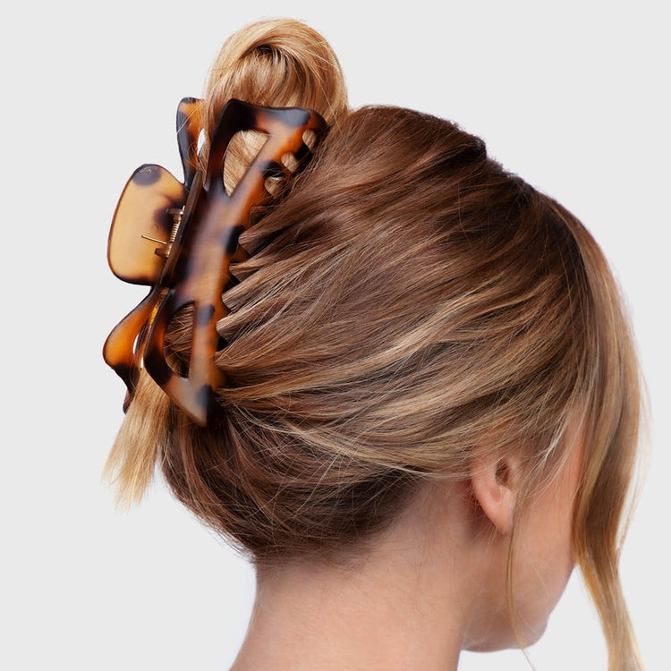 A woman wearing a large tortoiseshell-patterned jumbo classic claw clip in her blonde hair.
