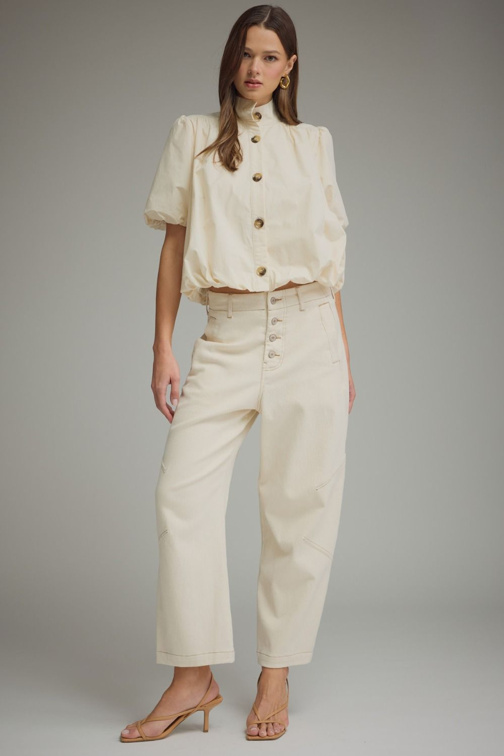 Woman wearing the Jacky cream short puff sleeve top with a bubble hem and band collar.