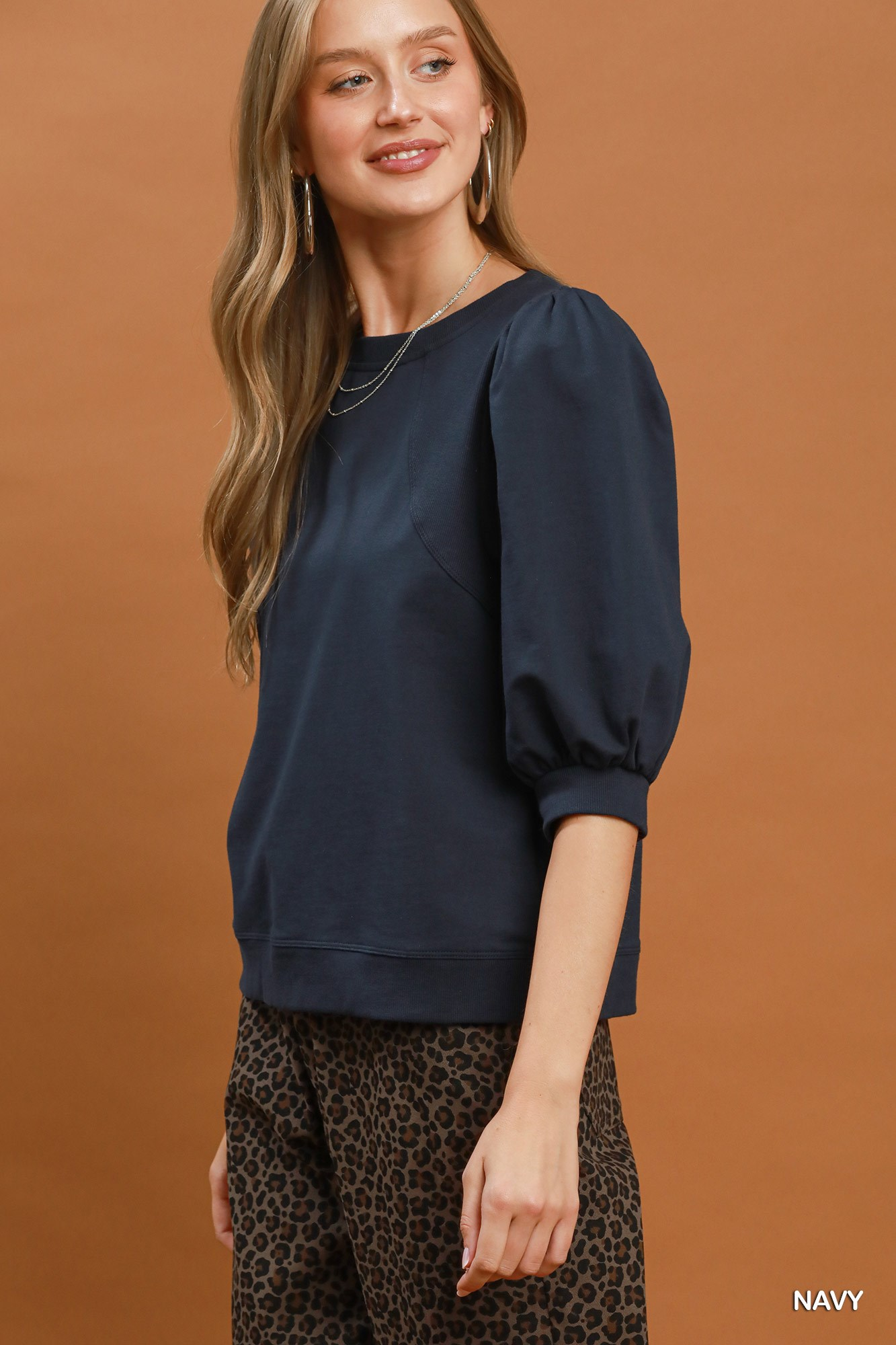 Woman wearing a navy Joyce Puff Sleeve Pullover Sweatshirt with leopard print pants.