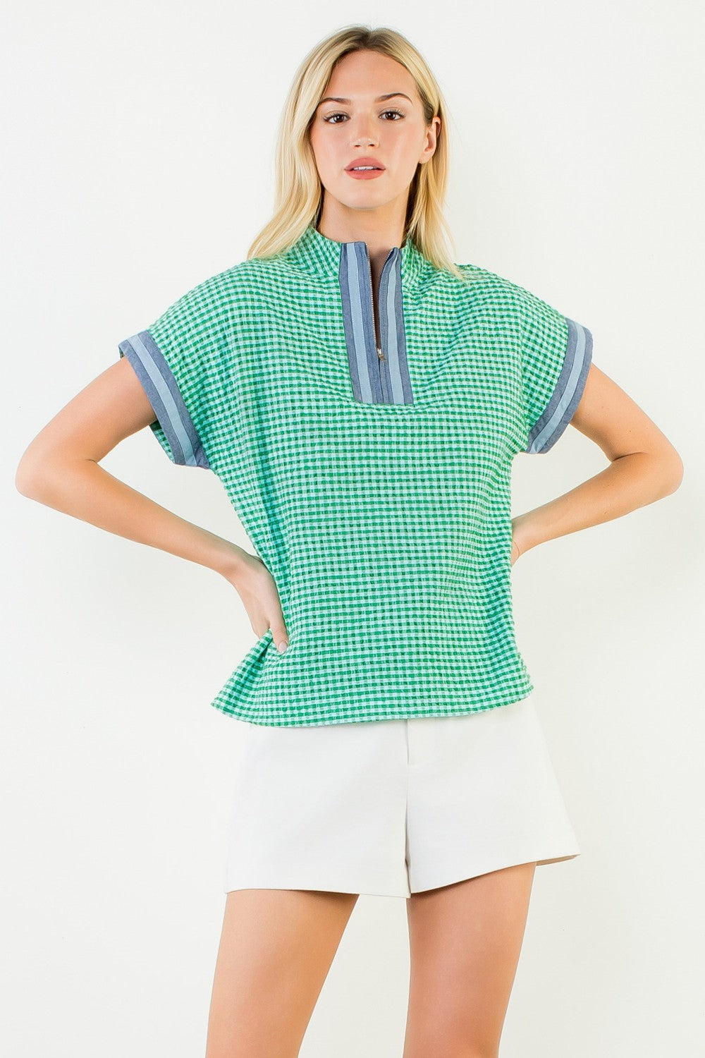 Woman wearing the Ariana green and white gingham short sleeve top with a quarter-zip neckline.