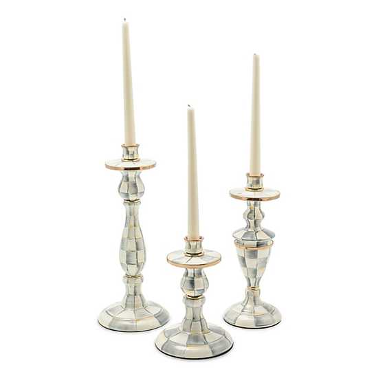 Three Sterling Check enamel candlesticks in varying heights with white taper candles.
