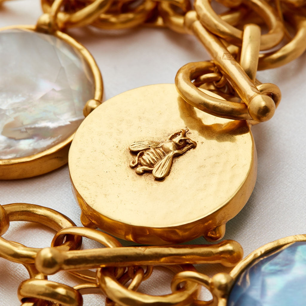 Close-up of a 24K gold plate toggle necklace featuring a raised honeybee on a round gold pendant.