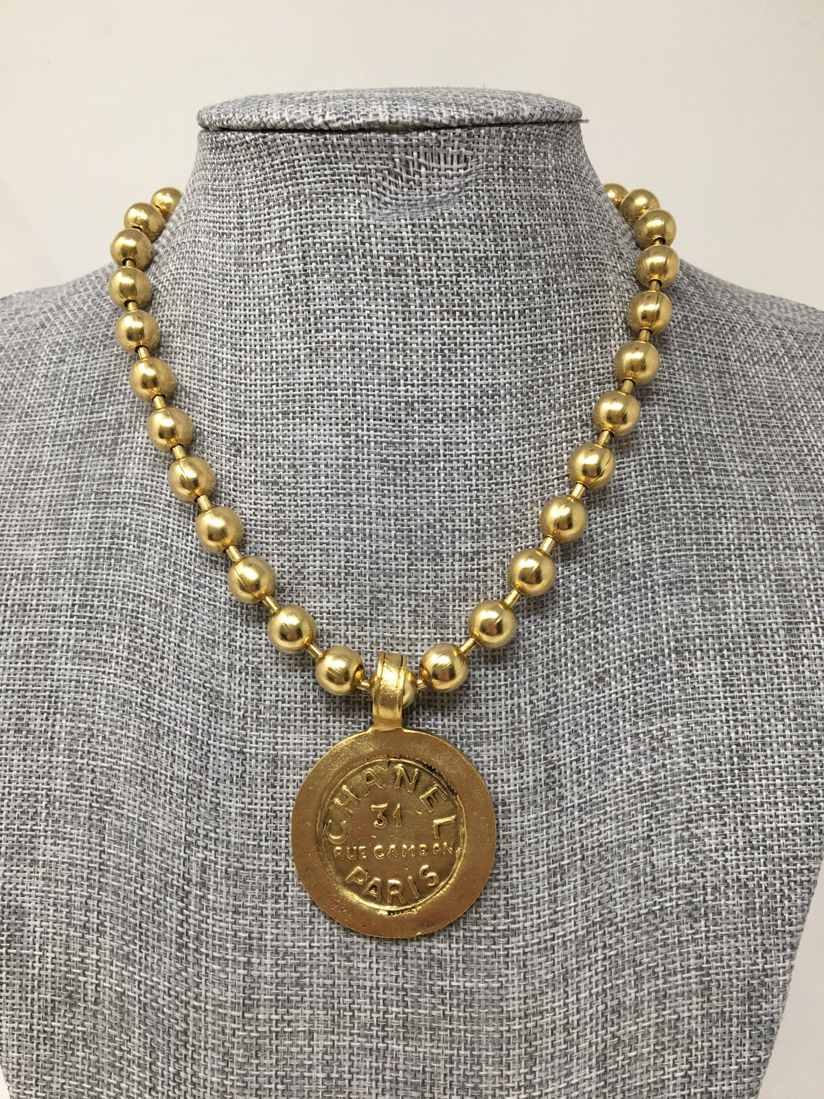 8-inch gold beaded necklace featuring a Chanel-style pendant with a 1.5-inch drop.