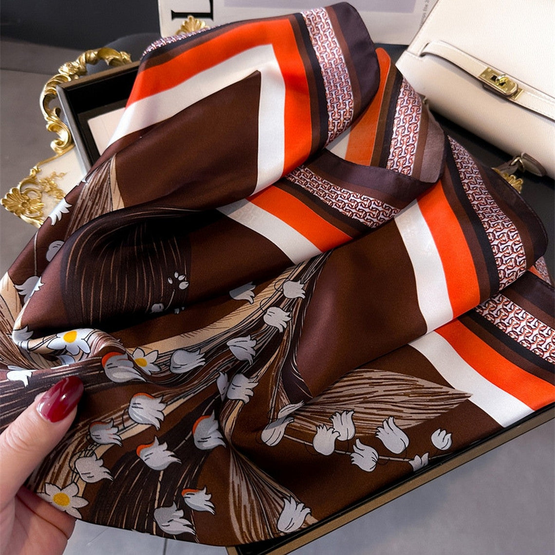 Artistic printed small square scarf in brown, orange, and white with floral and geometric patterns.