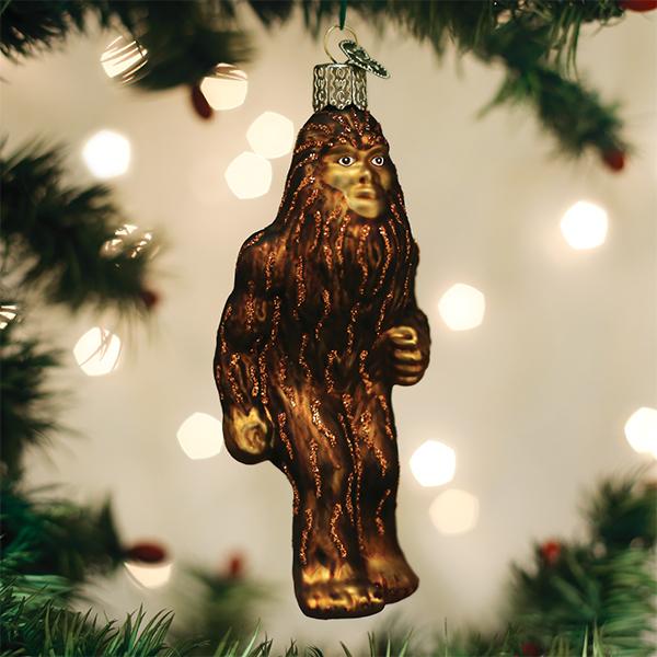 A brown glass Sasquatch ornament with glitter accents hanging on a Christmas tree.