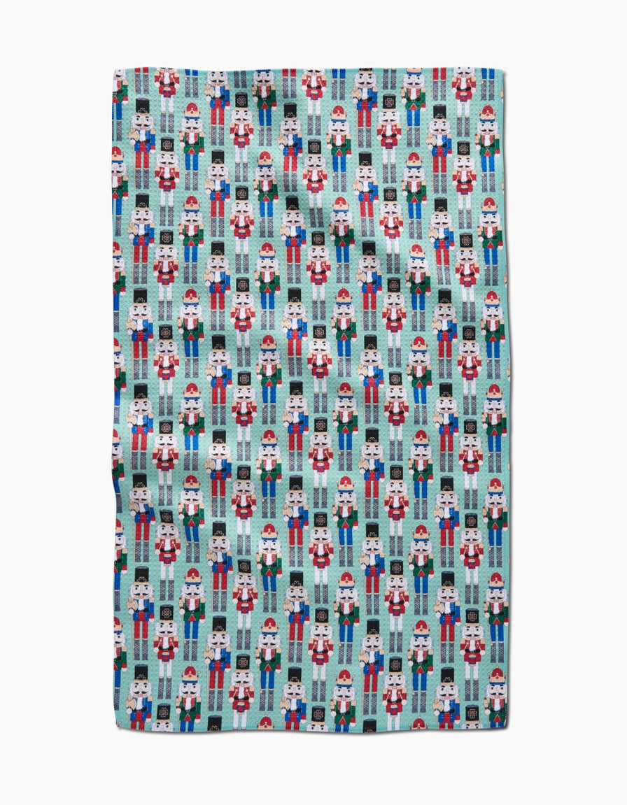 Holiday-themed kitchen tea towel with waffle weave texture in red featuring festive green holly and white snowflakes.
