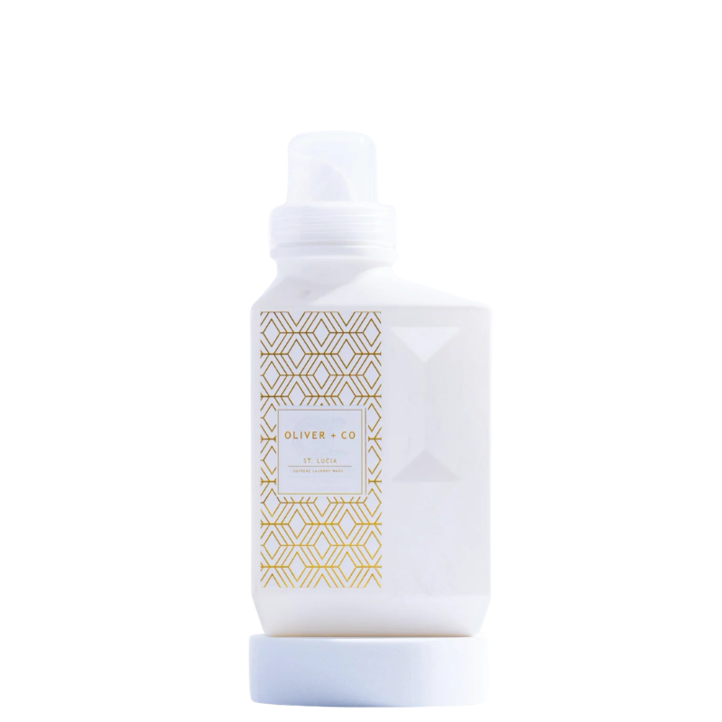 White bottle of Oliver + Co Supreme Laundry Wash with a gold geometric pattern on the label.