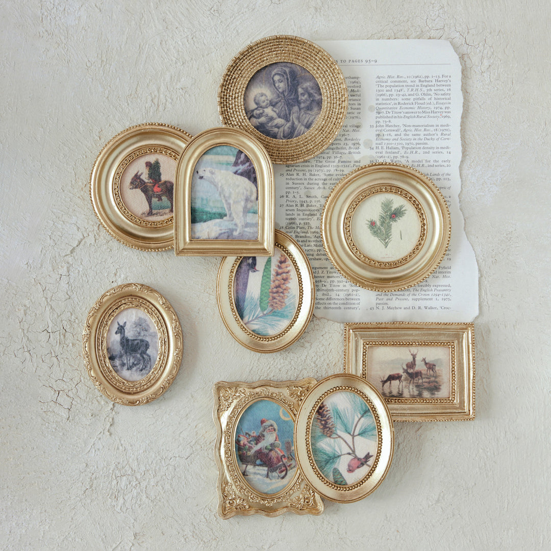 Assorted mini gold-framed vintage seasonal art magnets displayed on a textured wall.