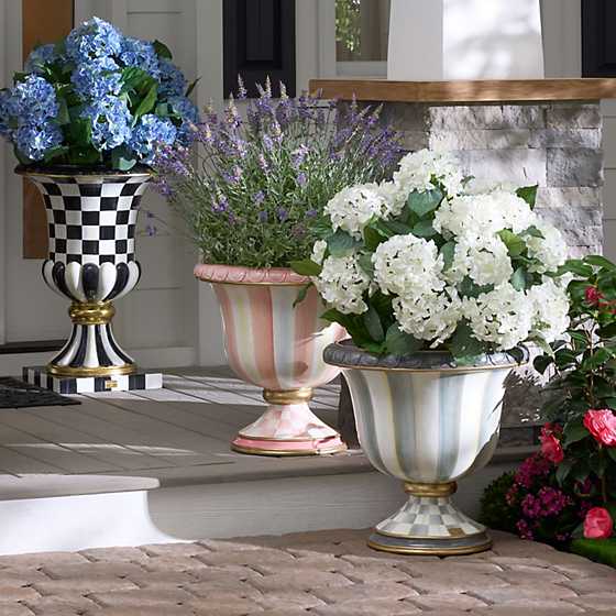 White artificial hydrangea urn filler displayed in a decorative striped garden urn on a porch.