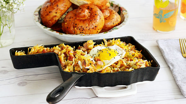 Oklahoma-shaped cast iron skillet filled with breakfast hash and a fried egg on a white table.