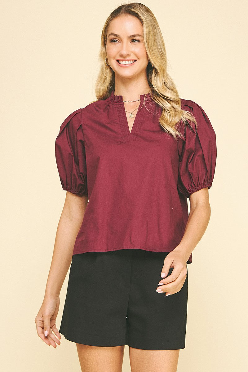 Ivy woven top in natural cotton with V-neckline, puff sleeves, and ruffle detailing at the neck.
