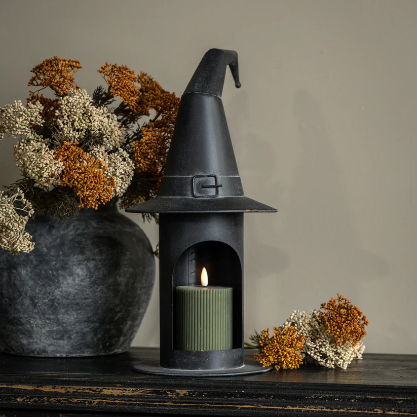 21.5 inch black metal witch's hat pillar candle holder on a dark wooden surface with fall florals.