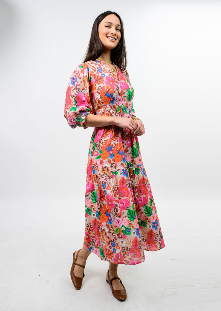 Woman wearing the Elise Floral Smocked Tiered Maxi Dress with puff sleeves and brown flats.